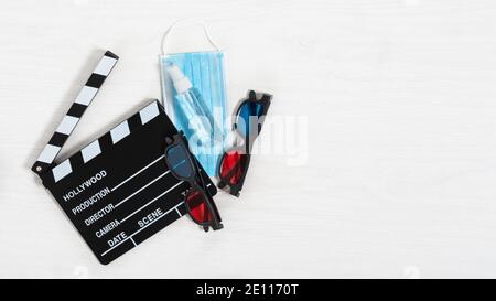 Tavoletta da cinema, occhiali 3d colorati e maschera anti virus e disinfettante per le mani su sfondo bianco in legno. Cinema nel concetto di tempo pandemico. Foto Stock