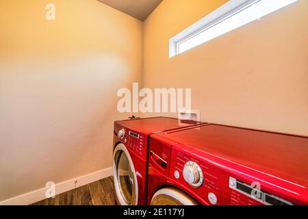 Lavatrice e asciugatrice di colore rosso brillante all'interno della lavanderia camera di casa Foto Stock