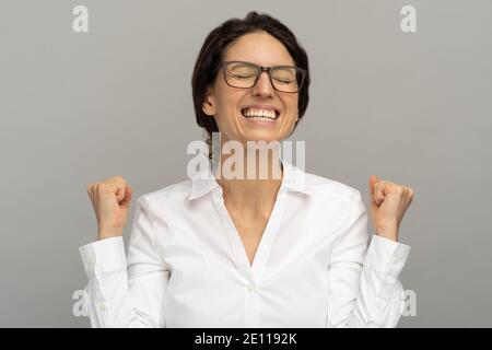 Il lavoratore riuscito dell'ufficio di vincita in occhiali che alzano i pugni celebra la carriera promozione o premio scala Foto Stock