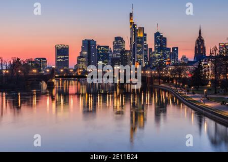 Skyline di Francoforte la sera al tramonto. Alti edifici dal quartiere finanziario e dal fiume Main con riflessi. Case illuminate Foto Stock