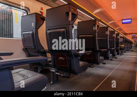 Sedili individuali in un'auto ferroviaria. Banchi di prima classe vuoti dalla ferrovia tedesca. Nessun passeggero nel vano del treno della corsia centrale. Illuminato c Foto Stock