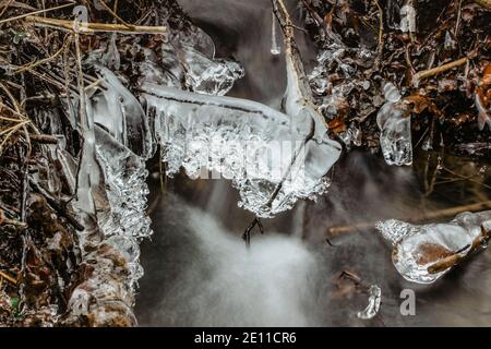 Primo piano di icicles vicino al ruscello selvaggio.Snowy scenario invernale.Icicle in natura ghiaccio background.freddo scivoloso tempo stagionale. Fila di icicles.Backgr gelosi Foto Stock