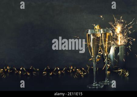 Due bicchieri di champagne con decorazioni scintillanti su sfondo scuro Foto Stock