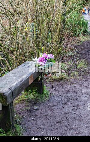 Fiori commemorati sulla panchina del sentiero pubblico Foto Stock