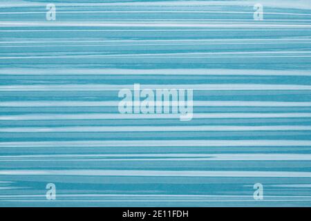 La pellicola adesiva piega la texture, la plastica, lo sfondo a strisce blu vinilico. Foto Stock