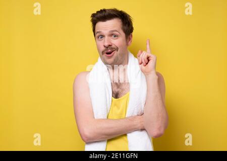 Uomo caucasico maturo che mostra il dito indice verso l'alto. Studio girato su parete gialla. Foto Stock