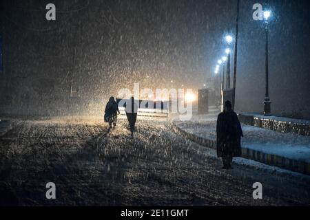 La gente del posto cammina lungo una strada coperta di neve durante una nevicata in Srinagar.moderata a nevicata pesante ha iniziato la domenica attraverso la valle del Kashmir tagliando la superficie della valle così come il collegamento aereo con il resto del mondo, ha detto i funzionari. L'uomo delle condizioni atmosferiche ha previsto una caduta di neve diffusa fino al 6 dicembre. Foto Stock