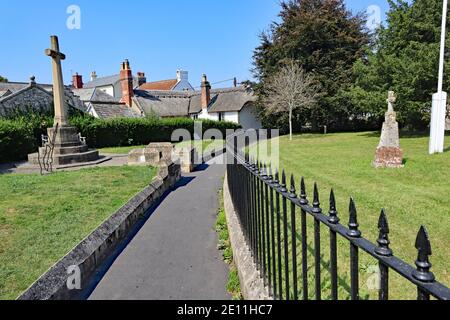 Un percorso stretto con ringhiere nere su un lato curve Intorno al bordo della chiesa di Colyton in Devon su un bella estate giorno Foto Stock