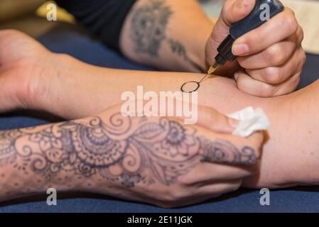 La persona fa il tatuaggio di Henna sul suo braccio - Mehndi Foto Stock