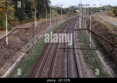 Ferrovia elettrificata. Due binari ferroviari vanno verso la città. Foto Stock