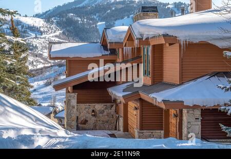 Casa con neve e ghiaccio contro il monte Park City Utah in un ambiente invernale Foto Stock