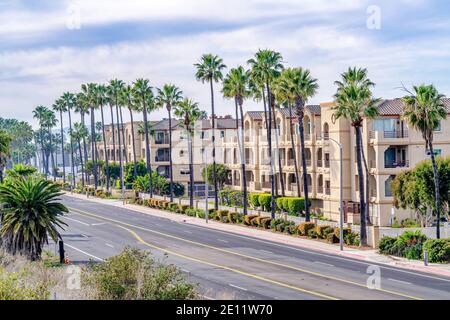 Edifici residenziali e strada fiancheggiata da palme a Huntington Spiaggia, California Foto Stock