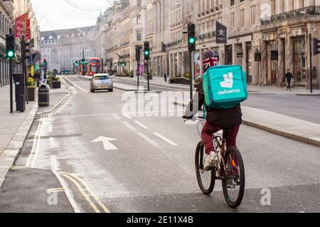 Londra, Regno Unito. 3 gennaio 2021. Il corriere Deliveroo corre lungo la Regent Street, fornendo cibo Takeaway nel centro di Londra durante le restrizioni di livello 4 del Covid 19. Credit: Pietro Recchia/SOPA Images/ZUMA Wire/Alamy Live News Foto Stock