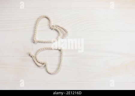 Composizione Flatlay con bellissimi cuori di corda carino su uno sfondo di legno bianco. San Valentino. Spazio di copia. Foto Stock