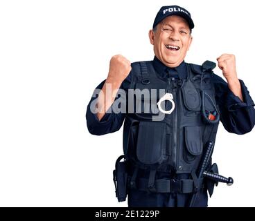 Uomo anziano bello che indossa uniforme della polizia gridando orgoglioso, celebrando la vittoria e il successo molto eccitato con le armi sollevate Foto Stock