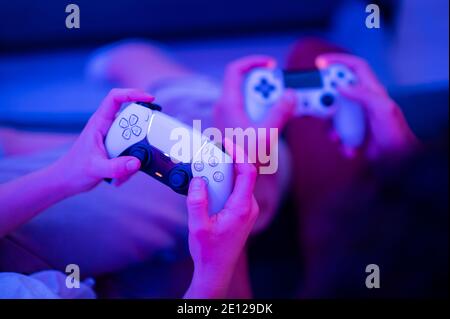 Ragazza che utilizza il nuovo controller wireless DualSense per PlayStation 5 Sony, che offre un feedback tattile coinvolgente, trigger dinamici adattativi e un integrato Foto Stock