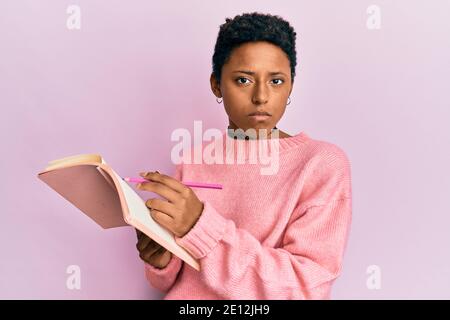 Giovane afroamericana ragazza lettura e scrittura libro depresso e preoccupazione per la sofferenza, piangendo arrabbiato e paura. Espressione triste. Foto Stock