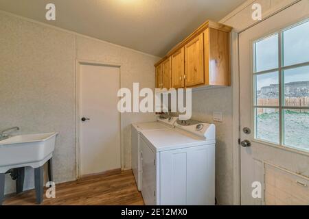 Lavanderia di casa con elettrodomestici e porta in vetro con vista sul cortile Foto Stock