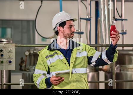 Tecnico addetto che controlla la bevanda nella macchina durante il processo in fabbrica Foto Stock