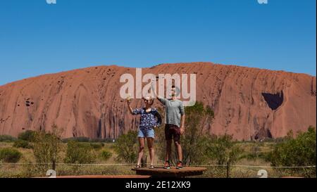 Uluru Australia Centrale. Due turisti prendono selfie al monolito di arenaria Uluru in Uluru -Kata Tjuta Parco Nazionale territorio del Nord, Foto Stock