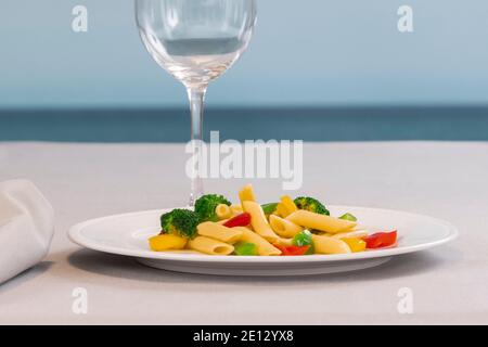 un piatto di insalata di pasta con un fuori fuoco vetro sul retro Foto Stock