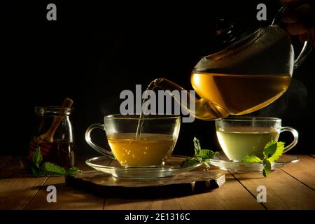 Primo piano di tè verde che viene versato dalla teiera in tazza Foto Stock