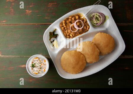 CHOLE CURRY E PURI SERVIRONO ALON CON CAGLIATA E SOTTACETI SU UNA PIASTRA DI CARTA Foto Stock