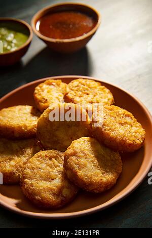 UN PIATTO DI ALOO TIKKIS SERVITO CALDO SU UN PIATTO CON SALSA E CHUTNEY Foto Stock