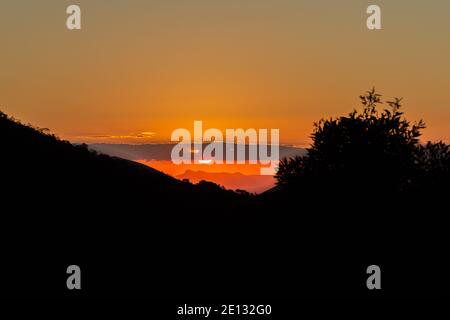 Cielo arancione durante il tramonto tra le montagne tra Teresopolis e. Petropolis nello Stato di Rio de Janeiro in Brasile Foto Stock