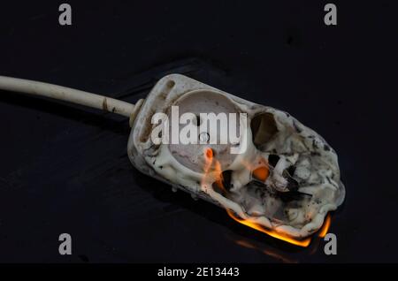 Concetto di sicurezza antincendio ed elettrica. Incendio del cablaggio elettrico. Basetta di alimentazione bruciata per le prese elettriche Foto Stock