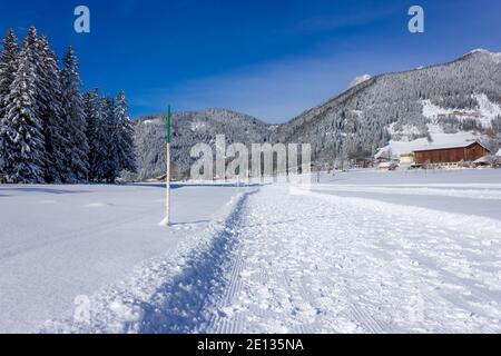 Paesaggio invernale innevato nelle Alpi con sentieri escursionistici e numerose montagne sullo sfondo (Ramsau am Dachstein, Austria) Foto Stock