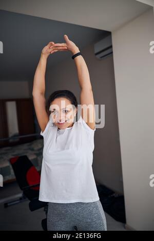 Sorridente donna in forma che si gode il suo allenamento stretching Foto Stock