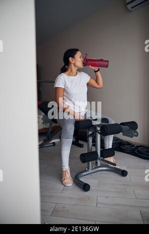 Donna sportiva che beve acqua da una bottiglia di plastica Foto Stock