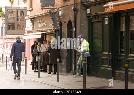 Uomo in abbigliamento da costruzione e donne che guardano alla vetrina di gioielleria. Immagine concettuale dei poveri e delle persone che raggiungono la strada. Foto Stock