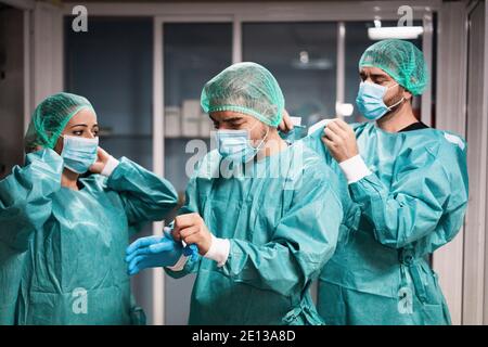 Medici e infermieri si preparano a lavorare in ospedale per l'intervento chirurgico durante l'epidemia di coronavirus pandemic - operatori medici che si vestono all'interno c Foto Stock