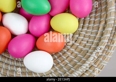 Colorate le uova di Pasqua, in un cesto di paglia contro uno sfondo grigio. Foto Stock