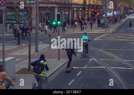 Trasporto alternativo. Persone in bicicletta, scooter e skateboard in via o’Connell. Dublino, Irlanda. Foto Stock