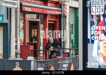 Vita quotidiana. Giovane uomo, che sembra sovrappeso, siede nel bar tailandese esterno nel centro di Dublino e gustando il suo spuntino. Foto Stock