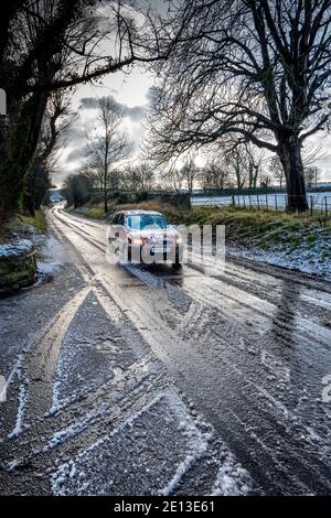 Auto che viaggia lungo una strada di campagna di scongelamento della neve. Foto Stock