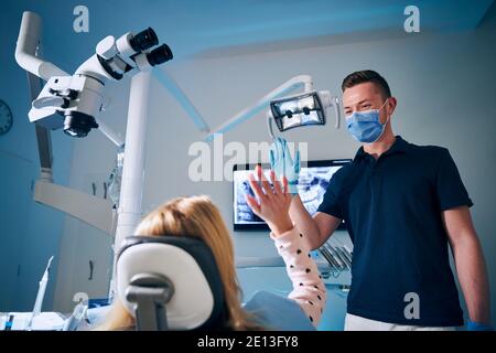 Supporto emozionale in ufficio dentista. Dentista che dà high-five alla ragazza nella chirurgia dentale moderna. Foto Stock