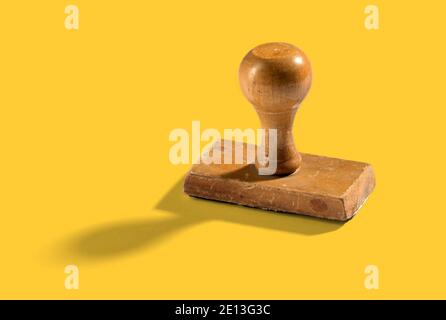 Francobollo in legno vintage in piedi verticale su sfondo giallo con un'ombra e uno spazio di copia accanto Foto Stock