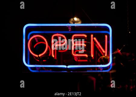 Primo piano su una luce al neon a forma di rettangolo blu e la parola "Apri" in rosso. Foto Stock