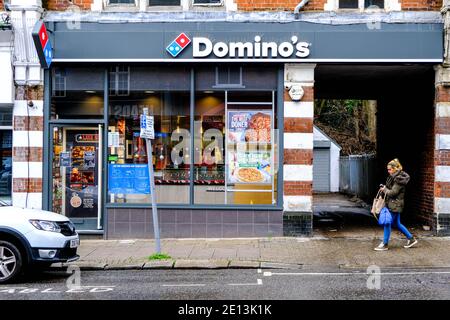 Epsom, Londra UK, gennaio 03 2021, Young Woman Shopper passerai accanto A un negozio Domino Pizza Take Away Foto Stock