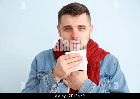 Giovane uomo con naso che cola su sfondo colorato Foto Stock