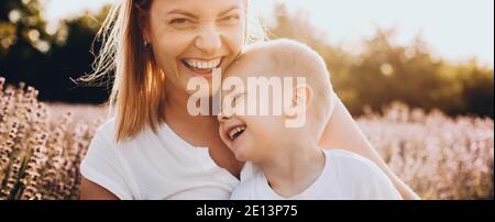 Affascinante figlio caucasico e sua madre sorridendo in una lavanda campo che guarda la telecamera Foto Stock