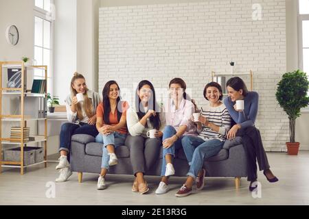 Gruppo di donne felici che parlano, divertendosi e gustando insieme una tazza di buon caffè Foto Stock