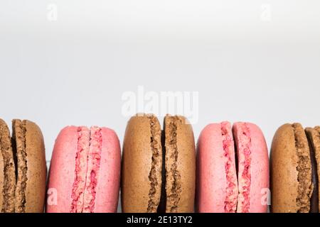 Un primo piano che mostra i bordi di cioccolato e fragola Meringa i amaretti con due metà meringa e ripieno su un sfondo bianco con copia spac Foto Stock