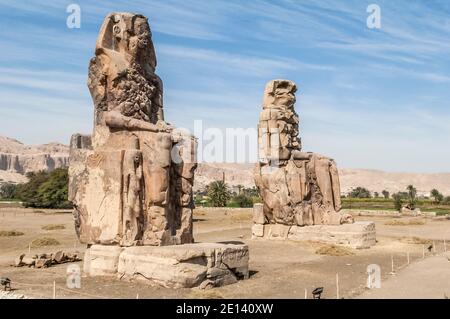 Questo è il sito archeologico del 1350 a.C. presso i Colossi di Memnone dell'Antico Egitto, non lontano dal fiume Nilo e dalla città di Luxor precedentemente conosciuta come Tebe. Le statue sono del faraone Amenhotep III, ci sono due statue più piccole ai suoi piedi, una è sua madre, l'altra sua moglie. Inizialmente costruiti per proteggere l'ingresso al tempio di Amenotep contro il male, sono stati anche visti per proteggere la riva occidentale del Nilo. I Colossi hanno sofferto di gravi danni sismici, ma dopo 3500 anni rimangono in piedi. Foto Stock