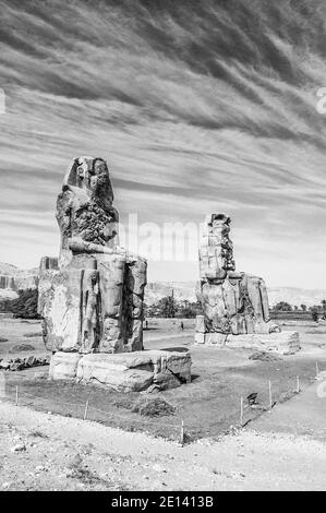 Questo è il sito archeologico del 1350 a.C. presso i Colossi di Memnone dell'Antico Egitto, non lontano dal fiume Nilo e dalla città di Luxor precedentemente conosciuta come Tebe. Le statue sono del faraone Amenhotep III, ci sono due statue più piccole ai suoi piedi, una è sua madre, l'altra sua moglie. Inizialmente costruiti per proteggere l'ingresso al tempio di Amenotep contro il male, sono stati anche visti per proteggere la riva occidentale del Nilo. I Colossi hanno sofferto di gravi danni sismici, ma dopo 3500 anni rimangono in piedi. Foto Stock