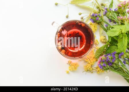 Fiori secchi, erbe e tazza di tè floreale su sfondo bianco Foto Stock